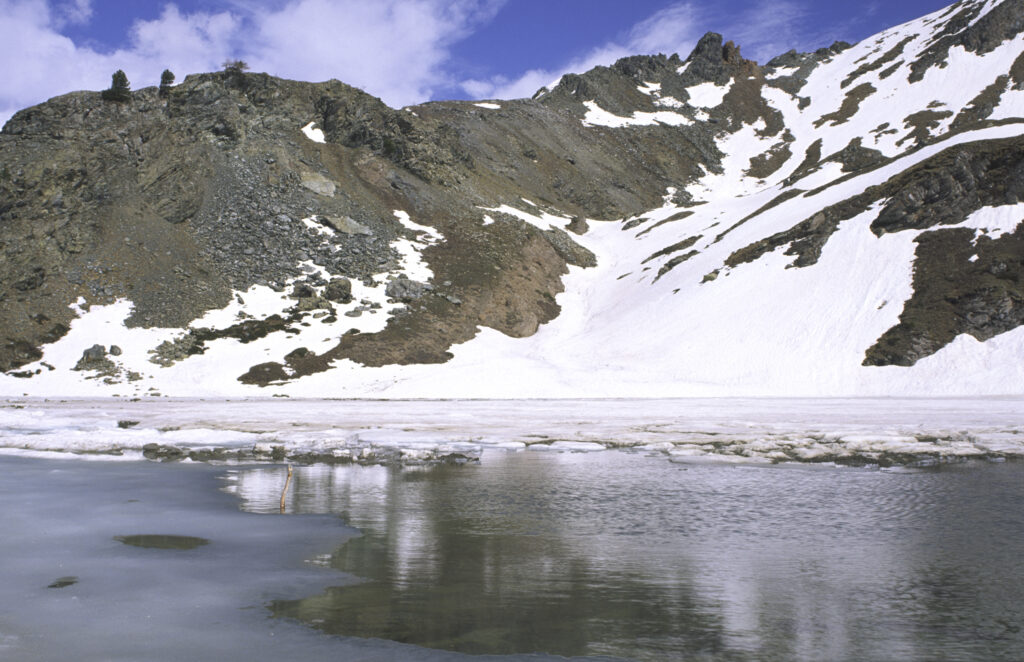 ITALY, Valle d'Aosta, Gran Paradiso National Park. The ice covered Lake Loie (lago di loie) in the peaks of the mountain landscape of the western Alps above the Lillaz valley.
