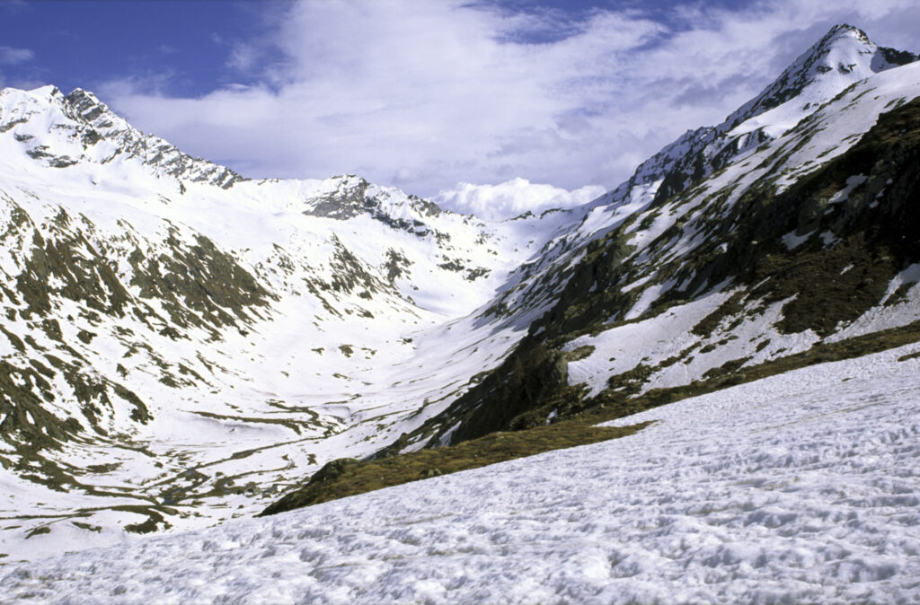 ITALY, Valle d'Aosta, Gran Paradiso National Park. Snow remains well into spring in the peaks of the mountain landscape of the western Alps and the valley near Bardoney.