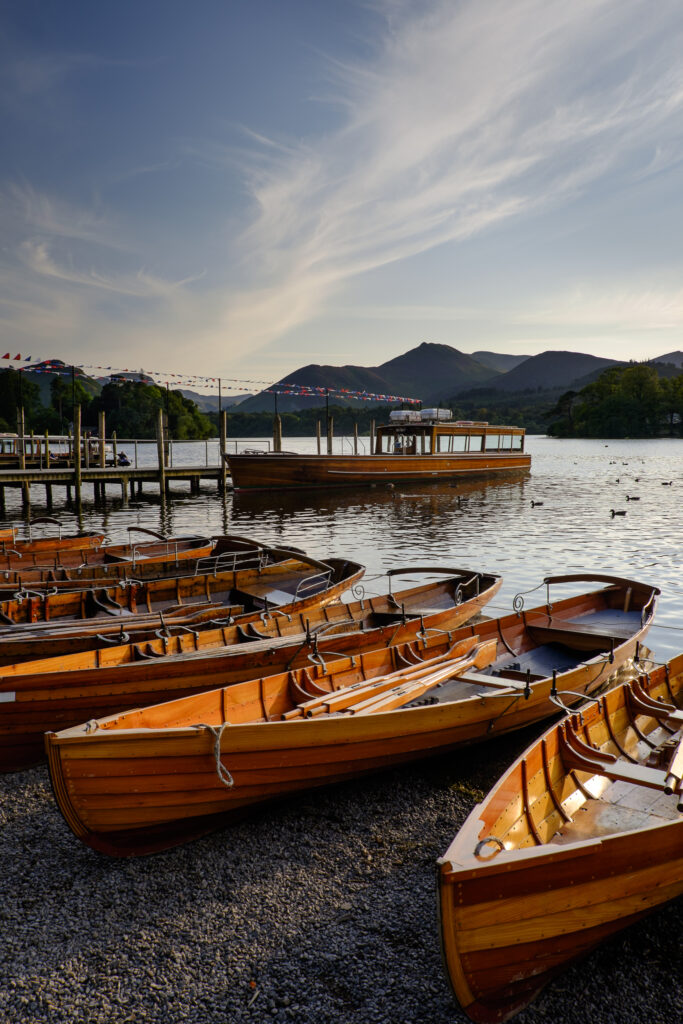 England, Cumbria, Lake District National Park. Wooden rowing boats and Derwent Water cruise ship moored at Keswick Jetty on Derwentwater -- Portal Editing Team selected this image for stockbyte.