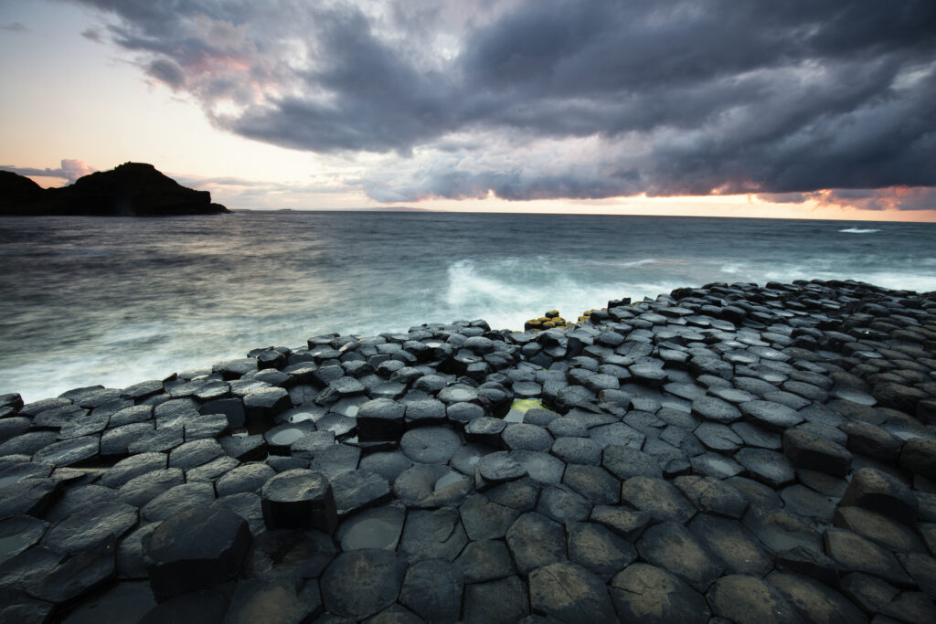 Northern Ireland, Country Antrim, Giant's Causeway. The sun sets behind the hexagonal basalt rock formations of Giant's Causeway Coast World Heritage site.