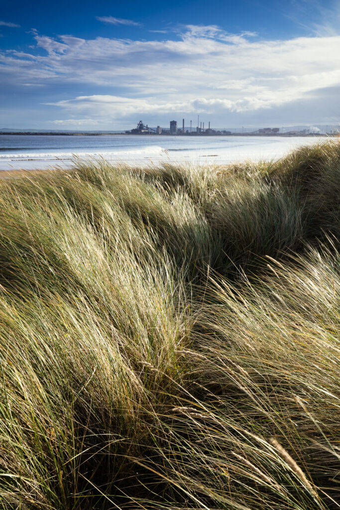England, Middlesbrough, Teesmouth NNR. Sand dunes at the Teesmouth National Nature Reserve near Seaton Carew with the Teeside Redcar Steel Works near Middlesbrough in the distance.