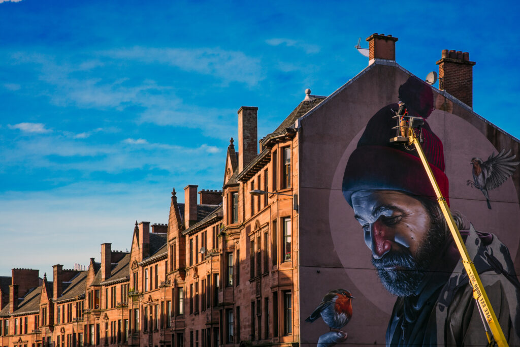 Scotland, Glasgow, Glasgow City. A workman painting a new Glasgow City Centre Mural - A project designed to embrace the concept of street art to promote the city centre, reduce the negative visual impact of land and unit vacancies due to the current economic circumstances, and provide features that will attract more visitors.