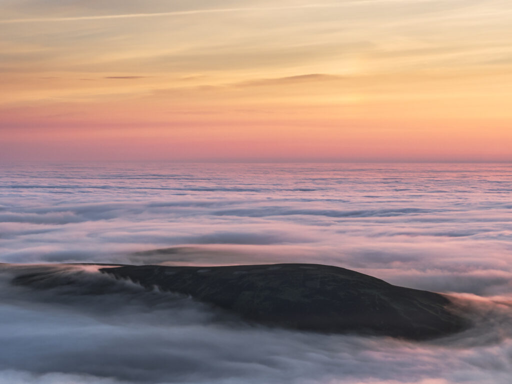England, Northumberland, Northumberland National Park. Dawn viewed from the summit of The Cheviot looking at a Northumberland hill just above a lake of mist caused by a temperature (cloud) inversion.