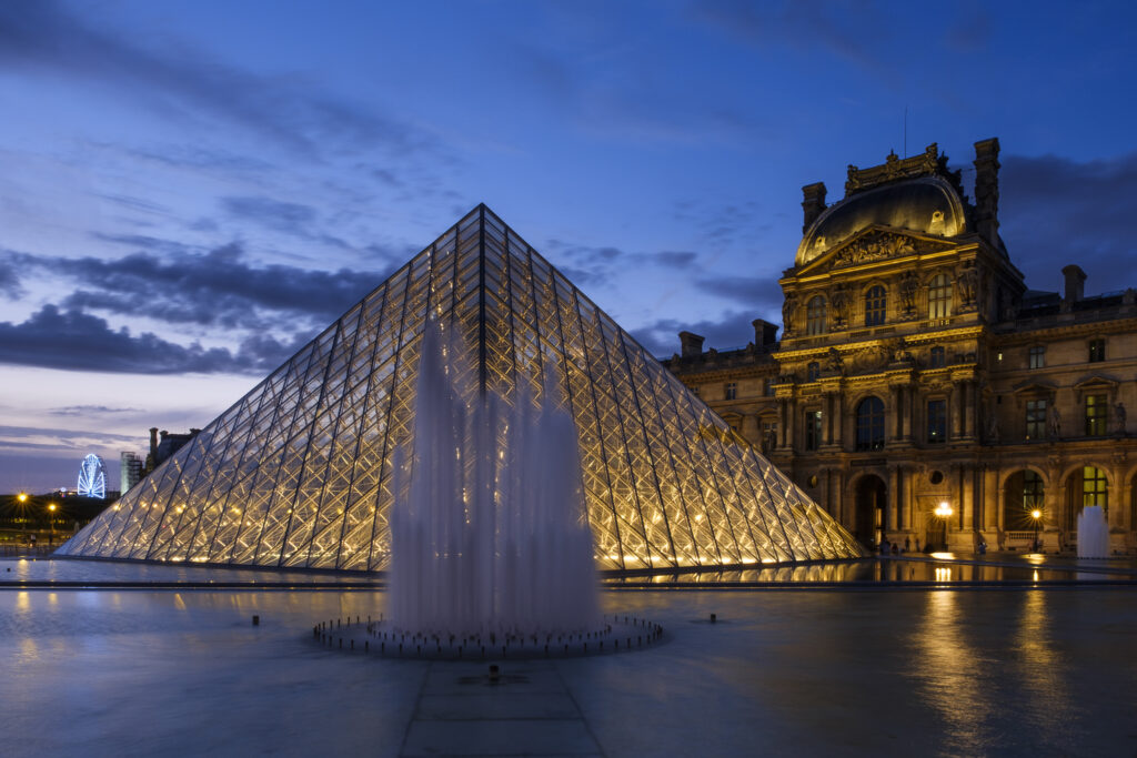 France, Paris, Louvre Museum. The Louvre Museum and Louvre Pyramid (designed by architect Leoh Ming Pei) illuminated at dusk.