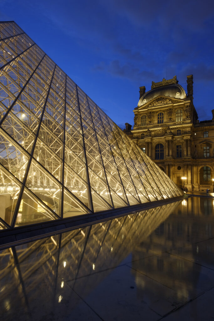 France, Paris, Louvre Museum. The Louvre Museum and Louvre Pyramid (designed by architect Leoh Ming Pei) illuminated at dusk.