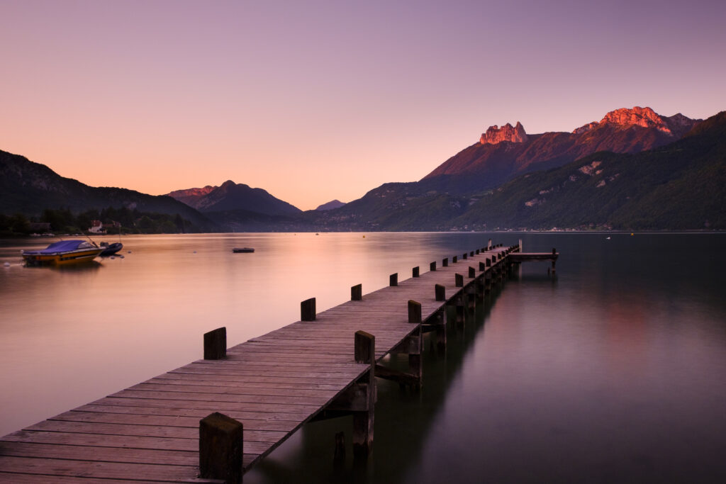 France, Auvergne-Rhône-Alpes, Lake Annecy. Dusk at Lake Annecy, viewed from a lakeside jetty near Doussard looking towards the Teeth of Lanfon on the east banks of the Lac d'Annecy in Haute-Savoie.