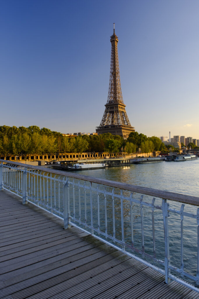 France, Paris, Eiffel Tower. Evening light on the Eiffel Tower viewed from the Passerelle Debilly, a footbridge spanning the River Seine which runs through Paris, the French capital city.