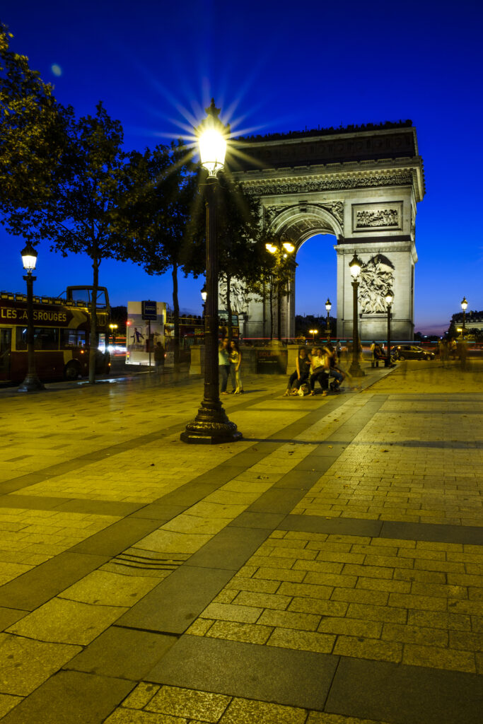 France, Paris, Arc de Triomphe. Pedistrian footpath on the Champs Elysees looking towards the Arc de Triomphe at dusk.