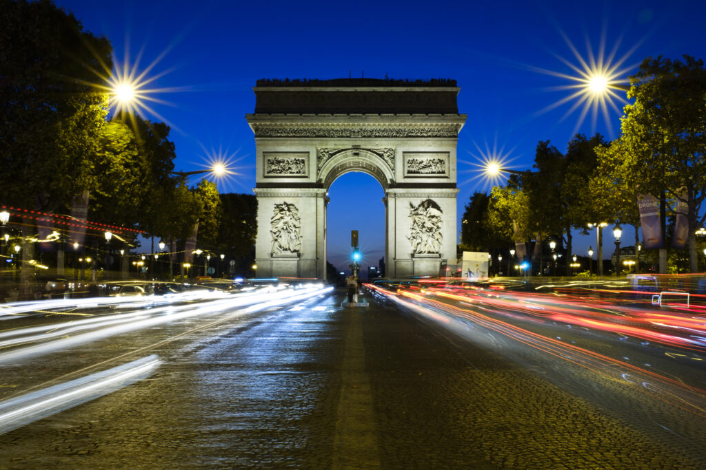 France, Paris, Arc de Triomphe. Busy traffic on the Champs Elysees looking towards the Arc de Triomphe at dusk.