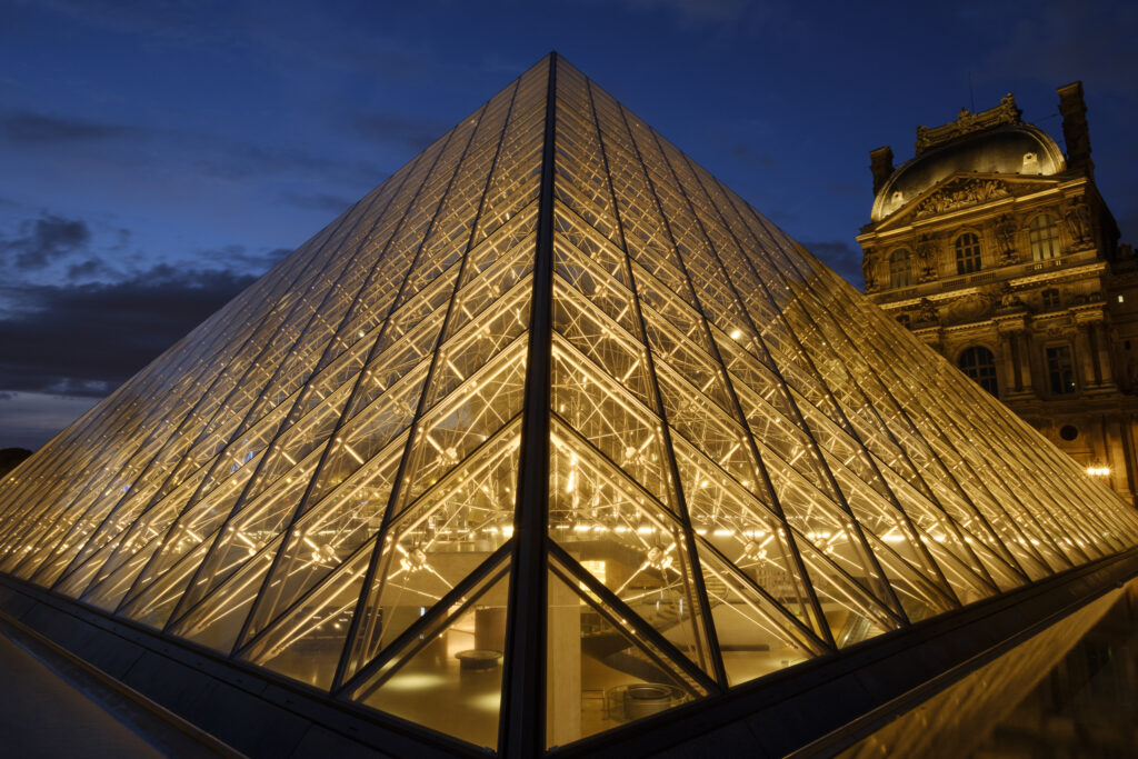 France, Paris, Louvre Museum. The Louvre Museum and Louvre Pyramid (designed by architect Leoh Ming Pei) illuminated at dusk.