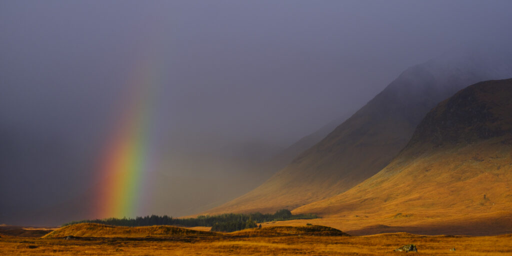 Scotland, Scottish Highlands, Rannoch Moor. A rainbow signalling a break in a storm above Rannoch Moor, revealing the surrouding mountains and hills.