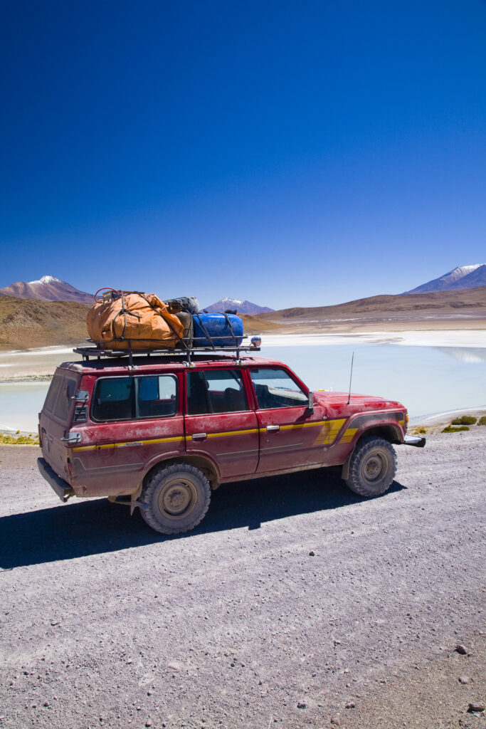Bolivia, Southern Altiplano, Uyuni Highlands. Jeep used for tourist trip parked near to a lake in the highlands.