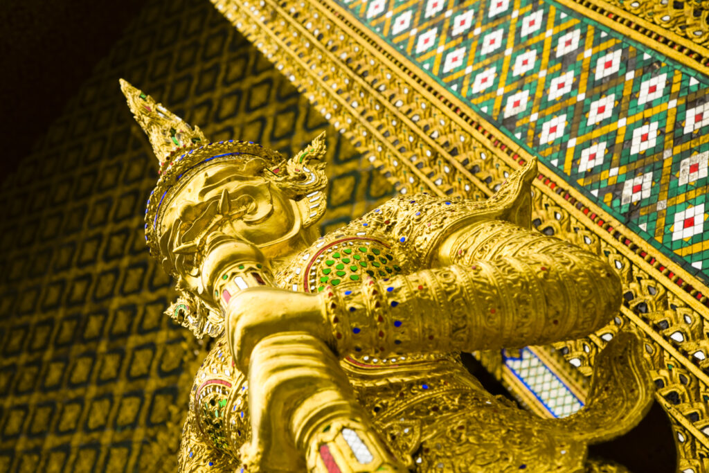 Thailand, Bangkok, The Grand Palace. Statue in the ornate setting of the golden grand palace.