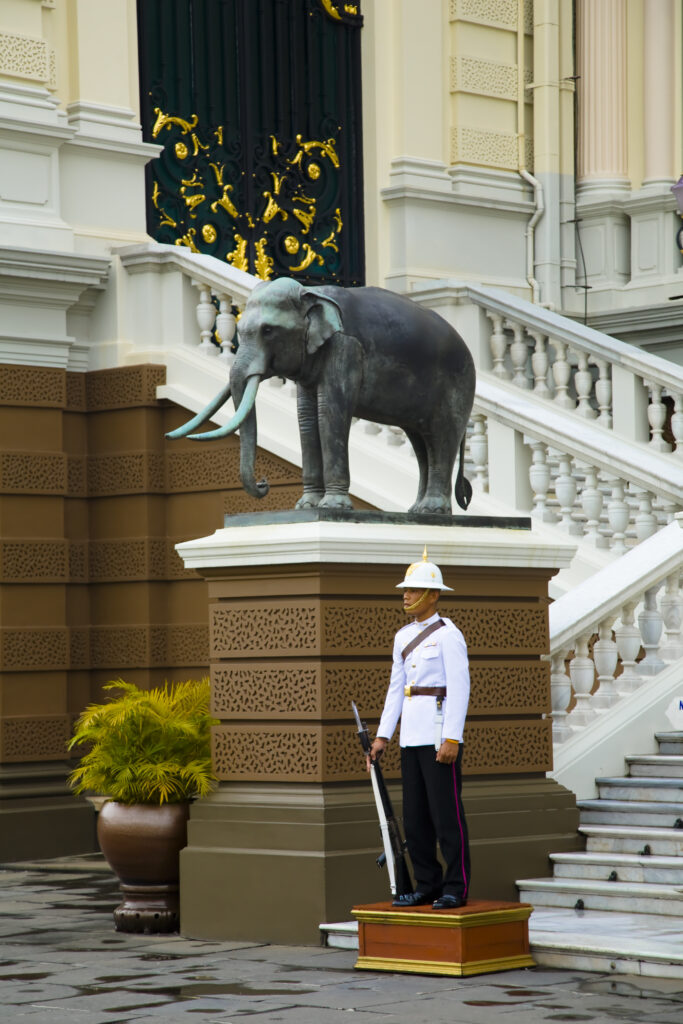 Thailand, Bangkok, The Grand Palace. Guard by a statue of an elephant, in the grand setting of the grand palace.