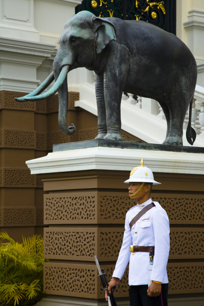 Thailand, Bangkok, The Grand Palace. Guard by a statue of an elephant, in the grand setting of the grand palace.