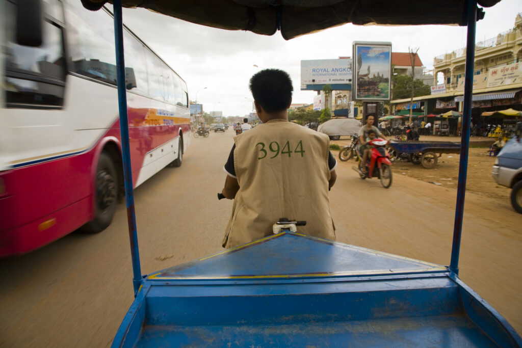 Cambodia, Siem Reap. Tut tut driver on a congested road in downtown Siem Reap near Angkor.