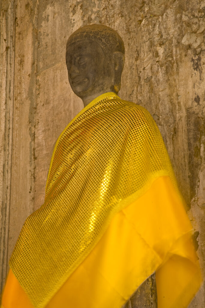 Cambodia, Angkor, Angkor Wat. Buddhist statues colourfully decerated within the dramatic remains of Angkor Wat.