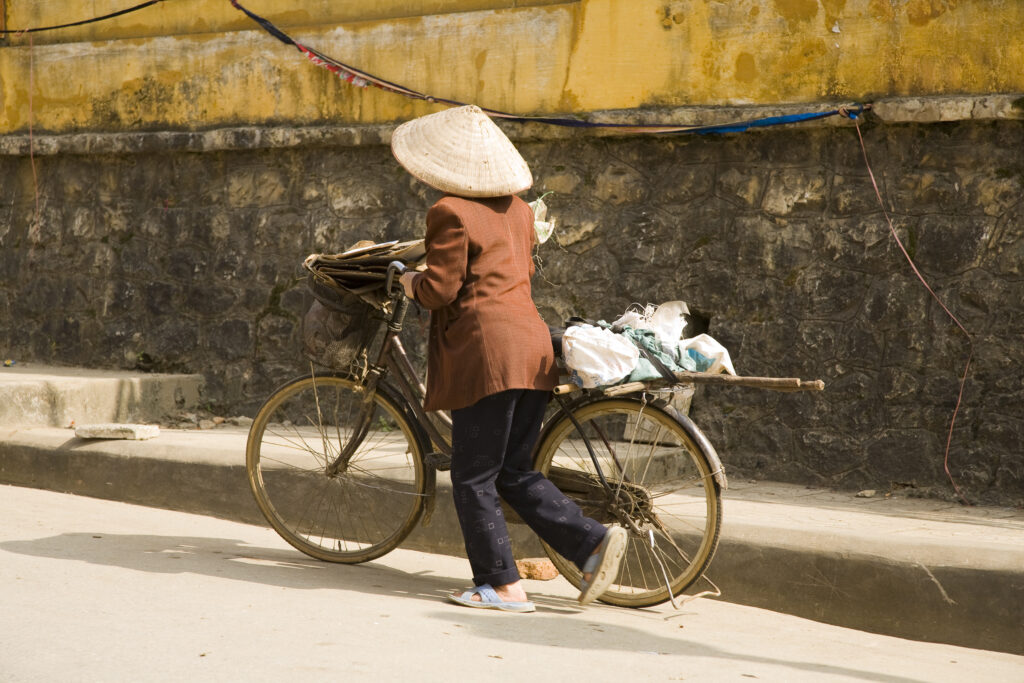 Vietnam, Northern Vietnam, Sapa. A local vietnamese woman pushes her bike along a street in Sapa.