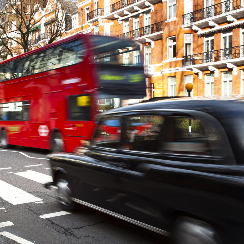 England, London, Abbey Road. A red London bus and Black Cab Taxi approach the famous pedestrian crossing at Abbey Road, made famous by the cover of the Beatles album of the same name.