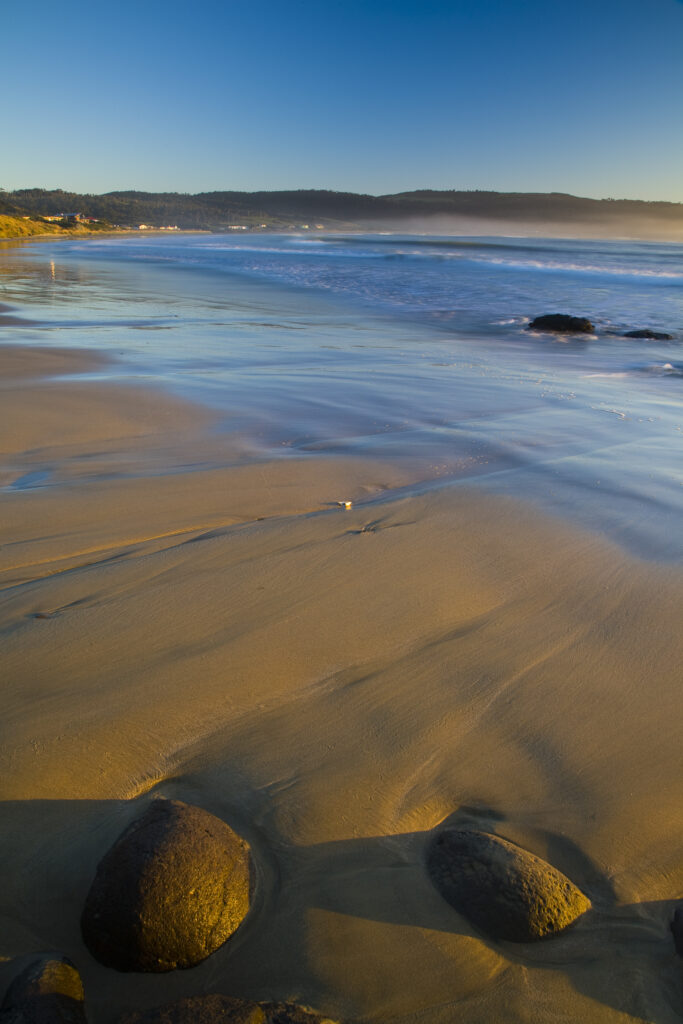New Zealand, Southland, The Catlins. Looking across the golden sands of Porpoise Bay shortly after sunrise.