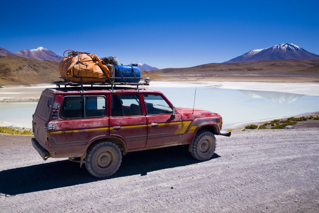 Bolivia, Southern Altiplano, Uyuni Highlands. Jeep used for tourist trip parked near to a lake in the highlands.
