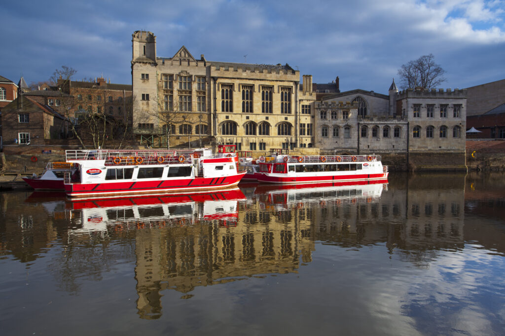England, North Yorkshire, York City. York city river cruise boats moored on the River Ouse with the Guildhall in the Background.