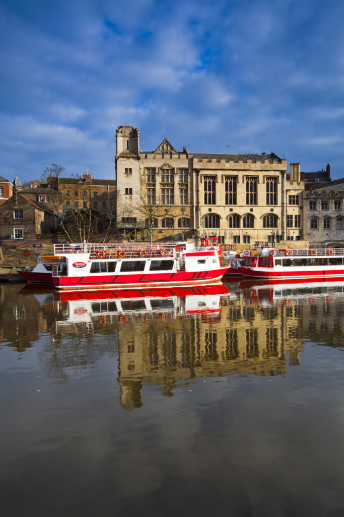 England, North Yorkshire, York City. York city river cruise boats moored on the River Ouse with the Guildhall in the Background.