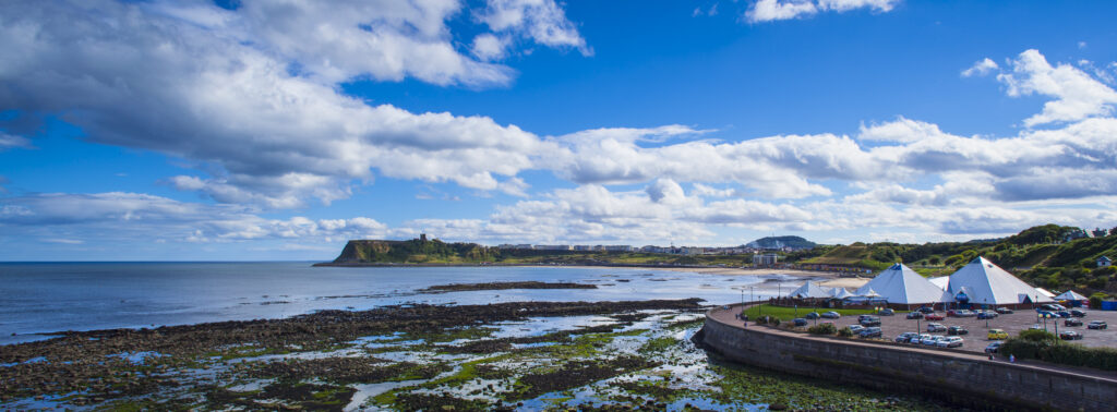 England, North Yorkshire, Scarborough. Panoramic view of the North Bay with Scarborough Castle in the distance.