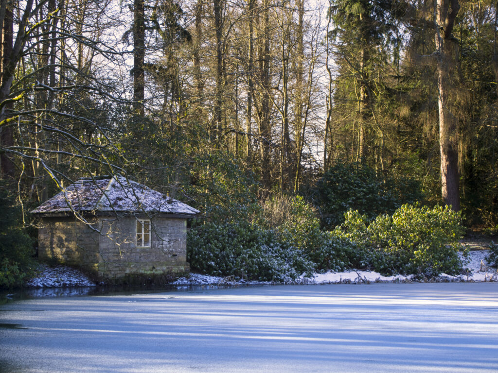 England, Northumberland, Wallington Estate. Stone builiding alongside an ice-covered lake in the Wallington Hall Estate (National Trust) in Northumberland, UK.