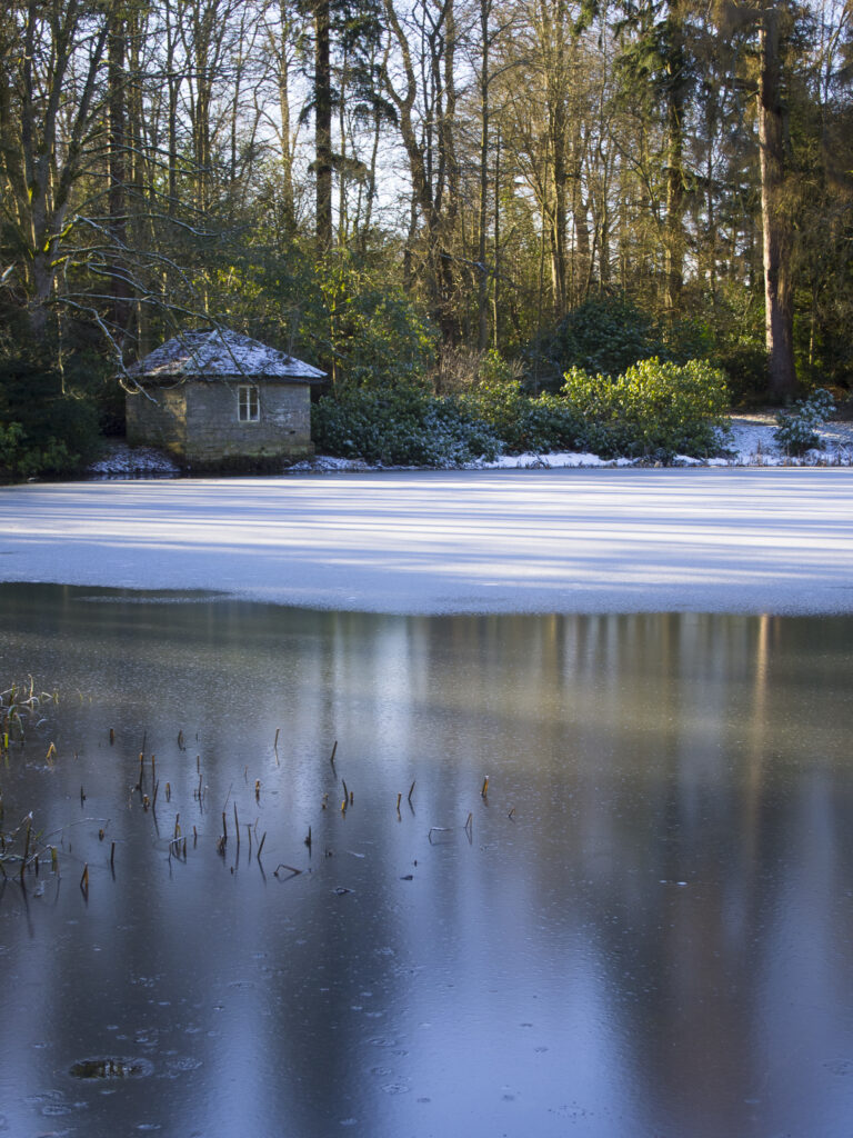 England, Northumberland, Wallington Estate. Stone builiding alongside an ice-covered lake in the Wallington Hall Estate (National Trust) in Northumberland, UK.