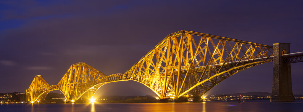 Scotland, Edinburgh, Forth Bridge. Forth Railway Bridge illuminated at night, connecting Scotland's capital city, Edinburgh, with Fife, leaving the Lothians at Dalmeny and arriving in Fife at North Queensferry.
