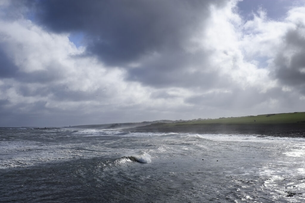 England, Northumberland, Craster. Rough sea and stormy sky on the Northumberland Heritage Coast near Dunstanburgh Castle.