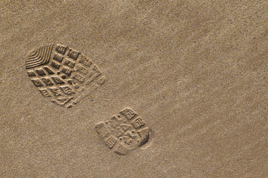 England, Northumberland, Bamburgh. Boot / Foot print on the sandy beach near Bamburgh along the Northumberland Heritage Coast.