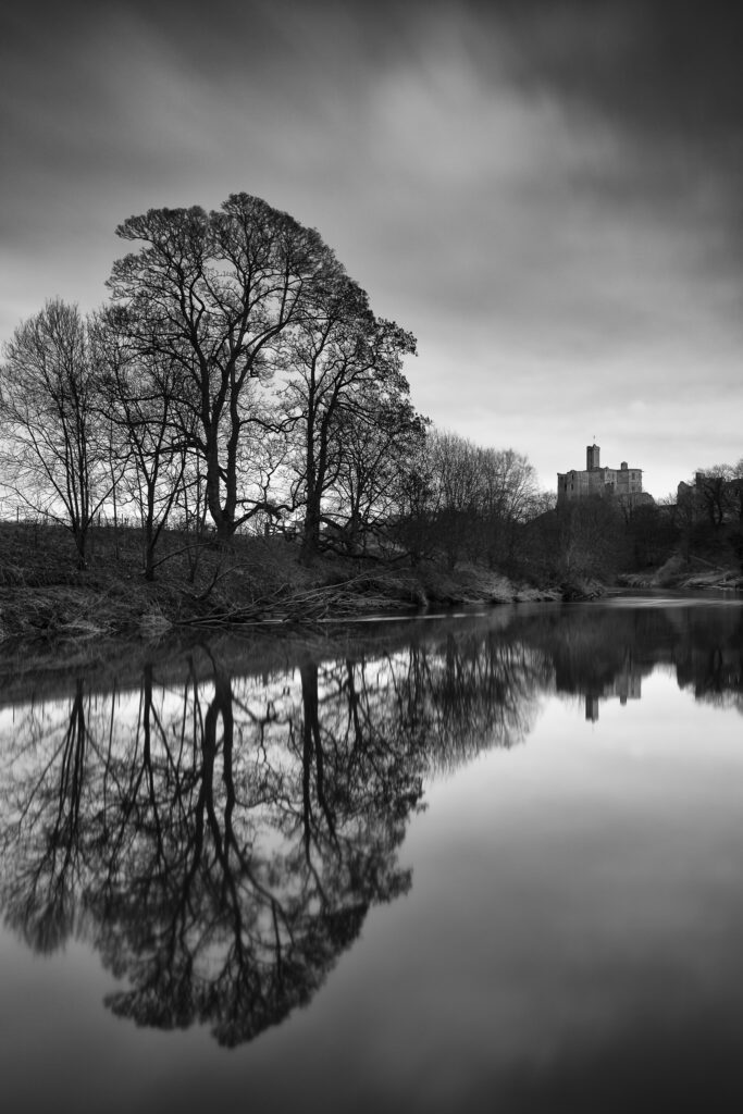 England, Northumberland, Warkworth. Warkworth Castle reflected upon the still waters of the River Coquet.