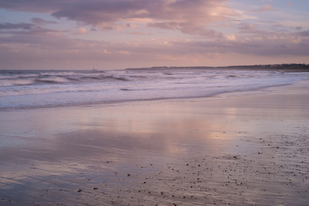 England, Northumberland, Blyth. Tranquil colours of sunset at Blyth South Shore looking towards St Marys Lighthouse.