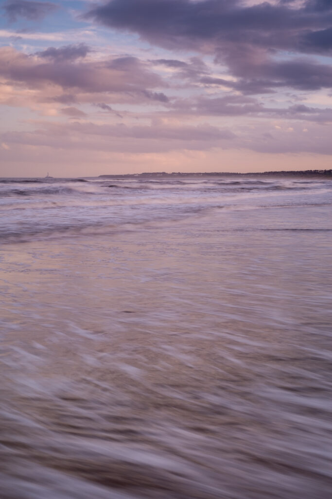 England, Northumberland, Blyth. Tranquil colours of sunset at Blyth South Shore looking towards St Marys Lighthouse.