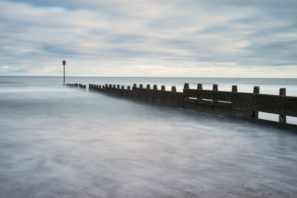 England, Northumberland, Blyth. Wooden groynes reaching out from the South Shore beach to the North Sea.