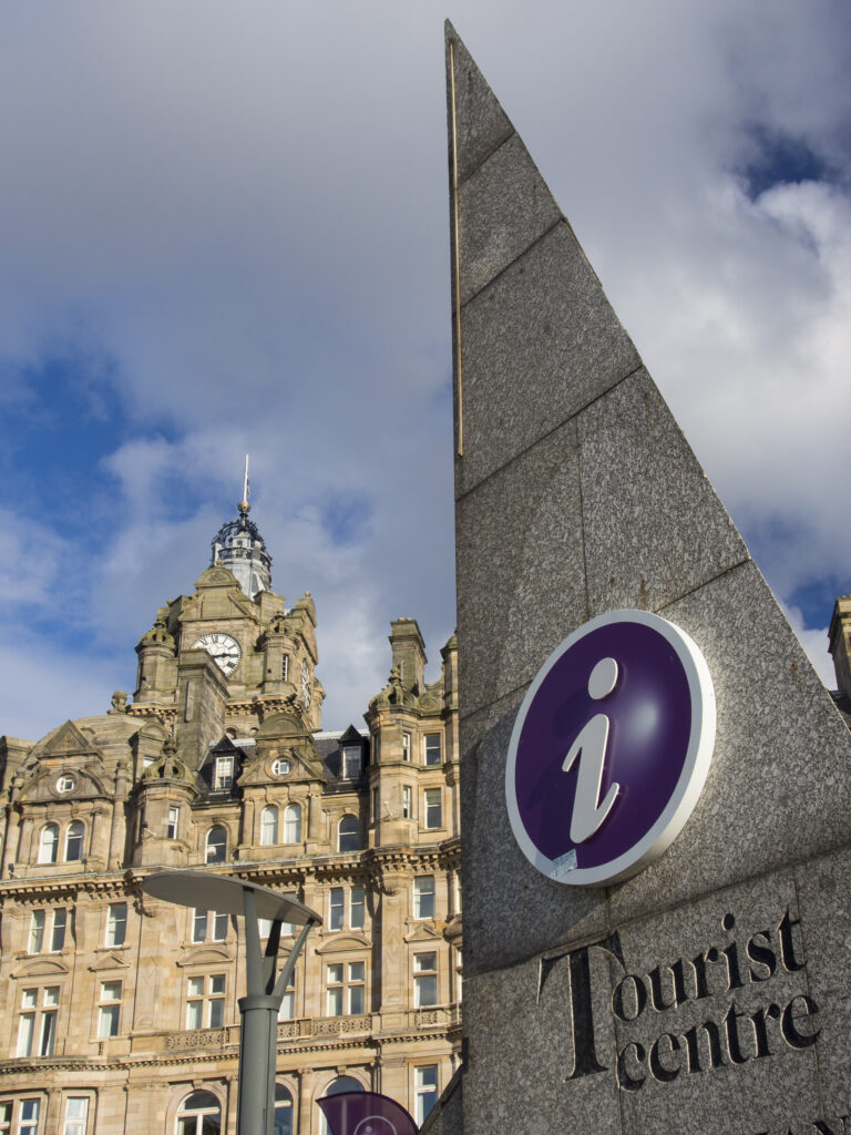 Scotland, Edinburgh, Edinburgh City. Edinburgh Tourist Centre sign with the Blamoral Hotel in the distance, often referred to as the most photographed clock tower in Scotland.