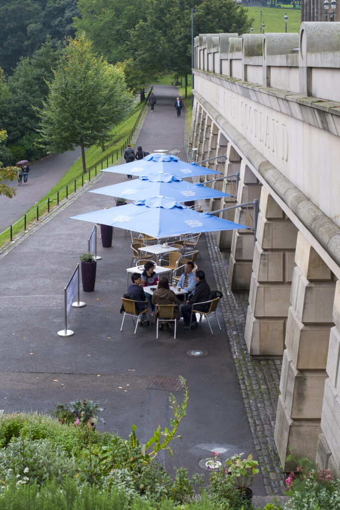 Scotland, Edinburgh, Princes Street Gardens. Tourists relaxing in a cafe outside the National Galleries of Scotland.