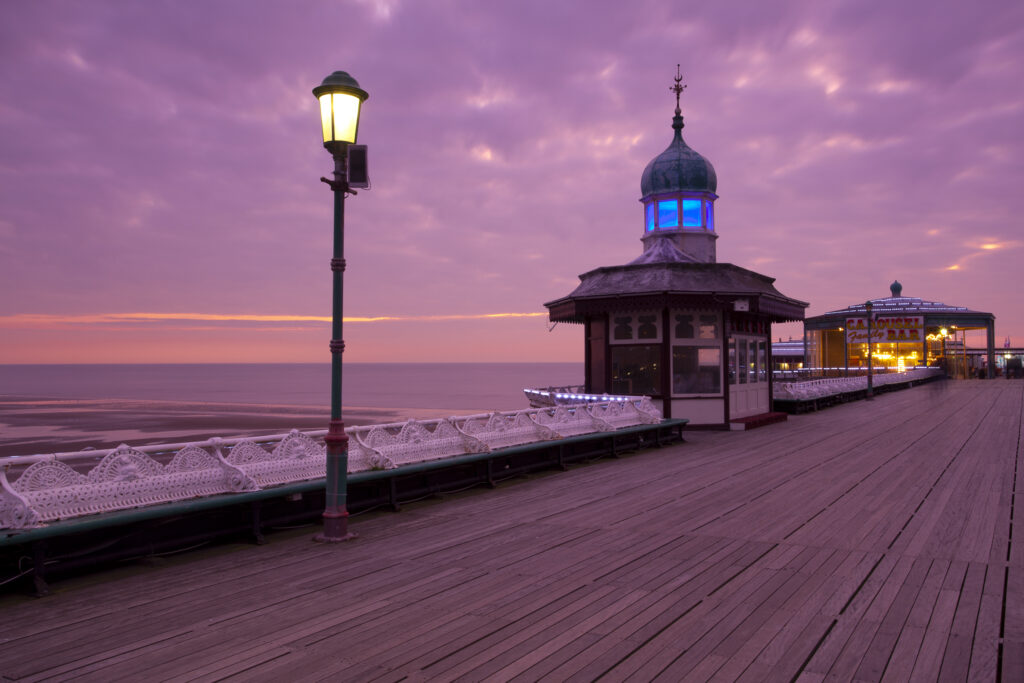 England, Lancashire, Blackpool. The pink hues of a sunset behind the Blackpool North Pier, an historic wooden pier located in the popular northern England seaside resort.