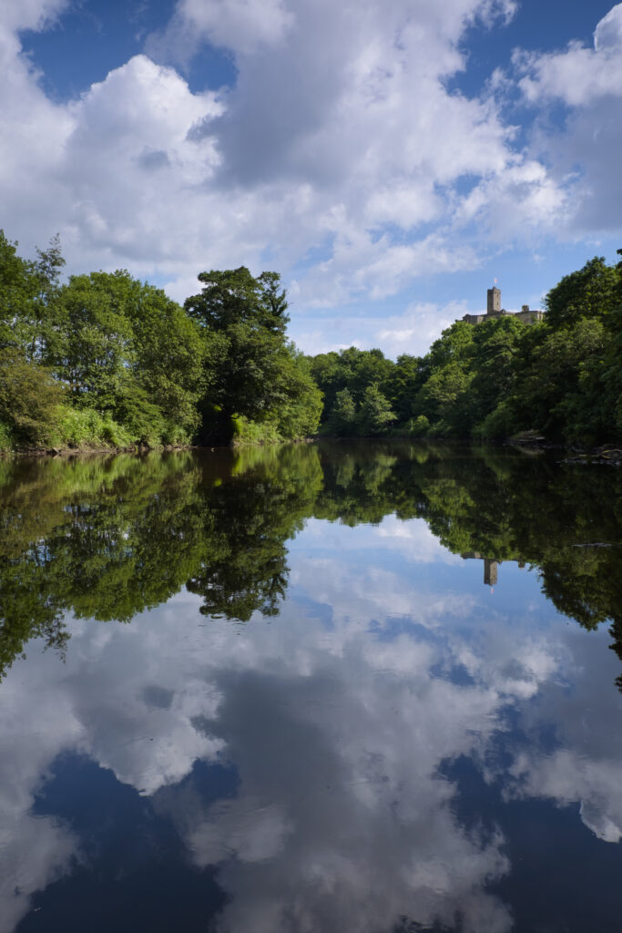 England, Northumberland, Warkworth. Warkworth Castle reflected upon the still waters of the River Coquet.