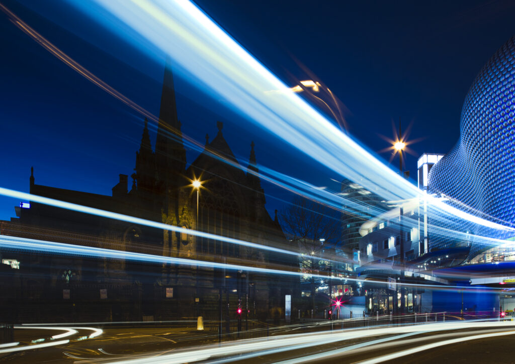 England, West Midlands, Birmingham City. Night time view of the new, modern Selfridges building, alongside the old St Martins Church.
