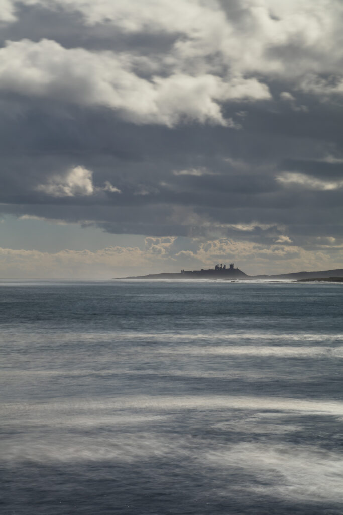 England, Northumberland, Beadnell. The imposing ruins of Dunstanburgh Castle viewed from Beadnell.