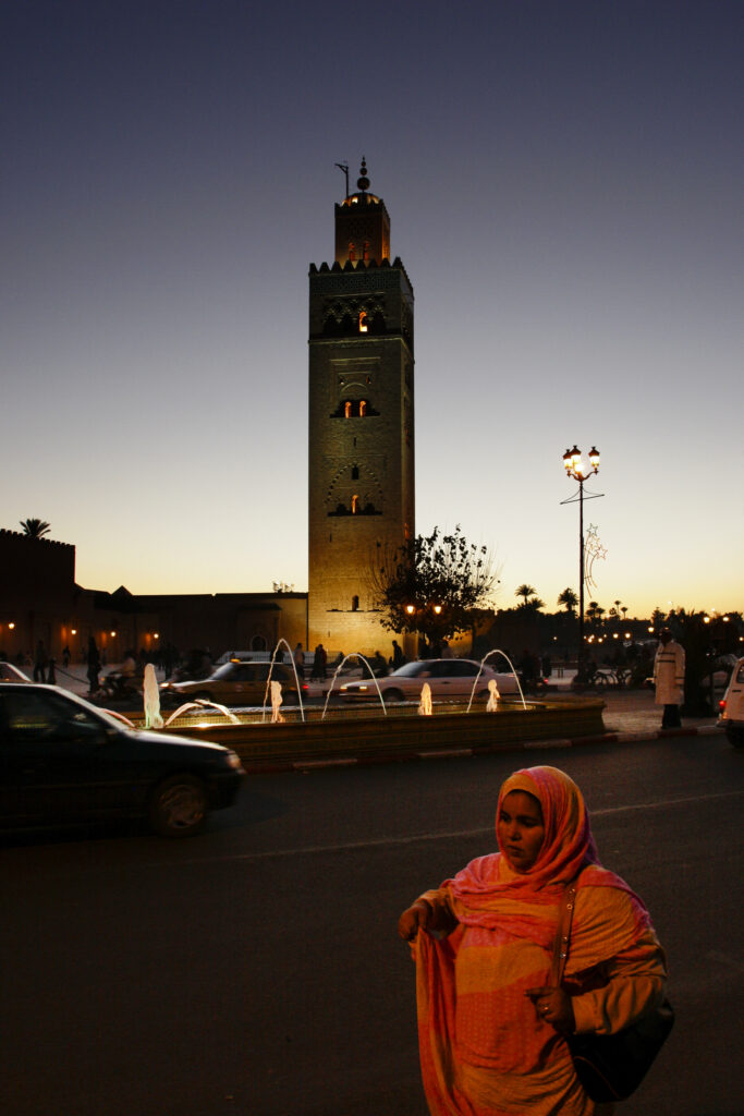 Morocco, Central Morocco, Marrakesh. Vehicle and pedistrian traffic by the Koutoubia Mosque, at dusk.
