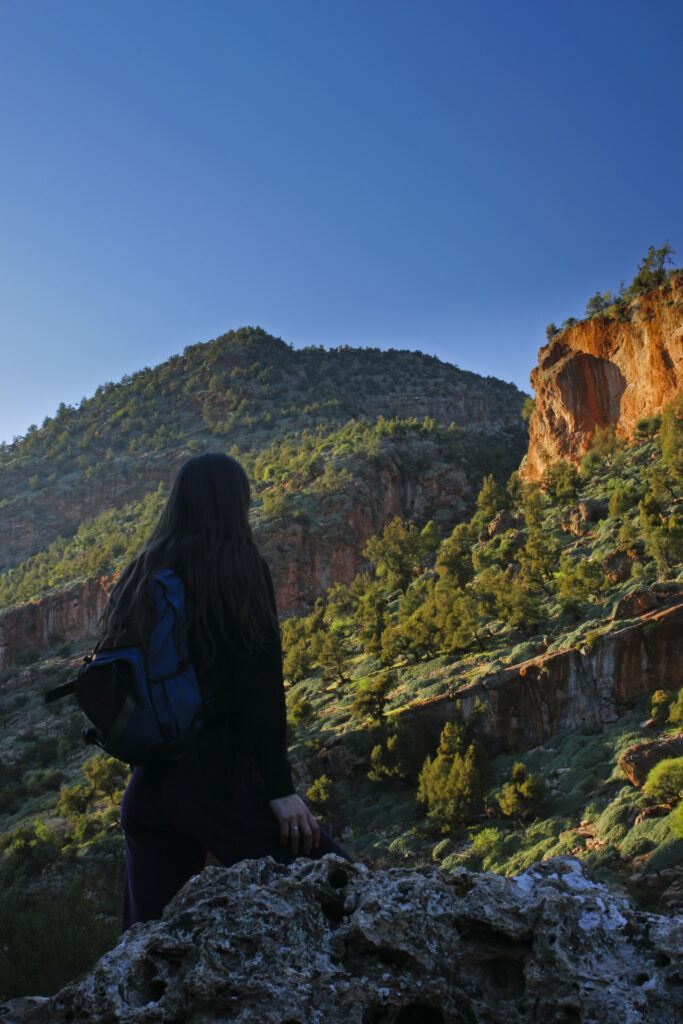 Morocco, Central Morocco, The Ouzoud Gorge. A female hiker admires the wild landscape of the gorge and hills.