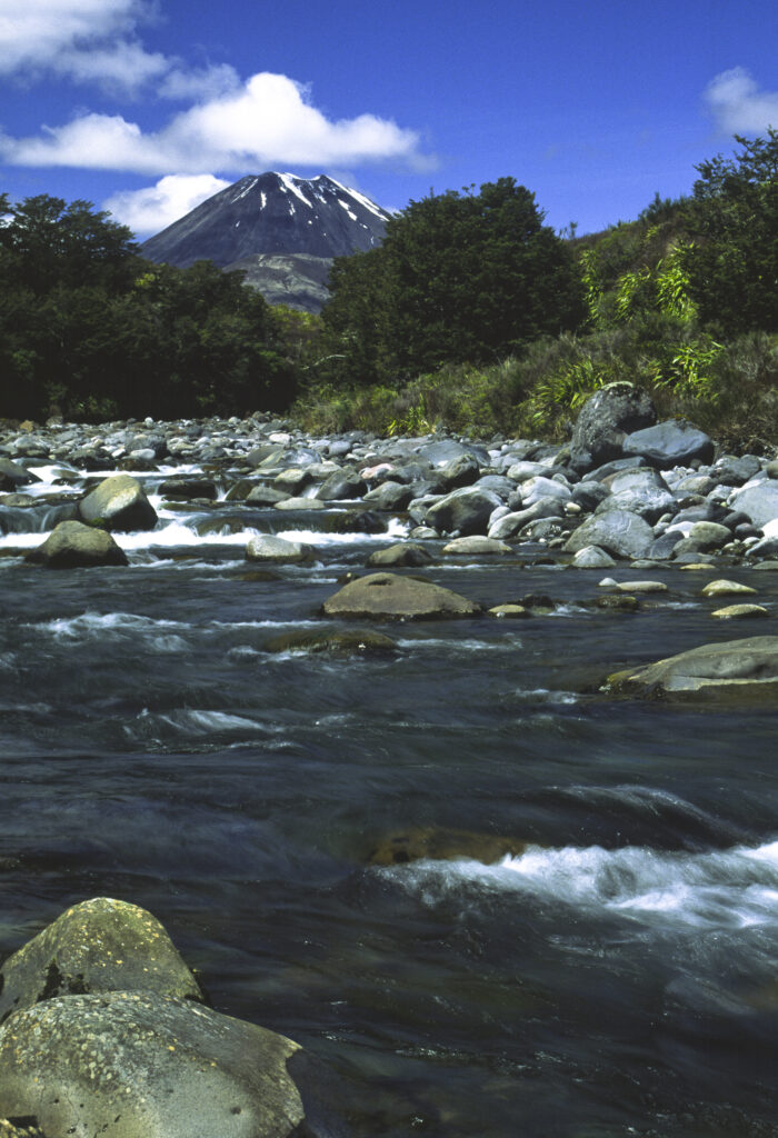NEW ZEALAND, Central Plateau, Tongariro National Park. Mahuia rapids with the dormant volcanoe Mt Ngauruhoe in the distance