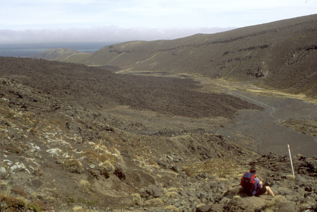 NEW ZEALAND, Central Plateau, Tongariro National Park. Tramper looking back towards the route hiked on the Tongariro Crossing Track.