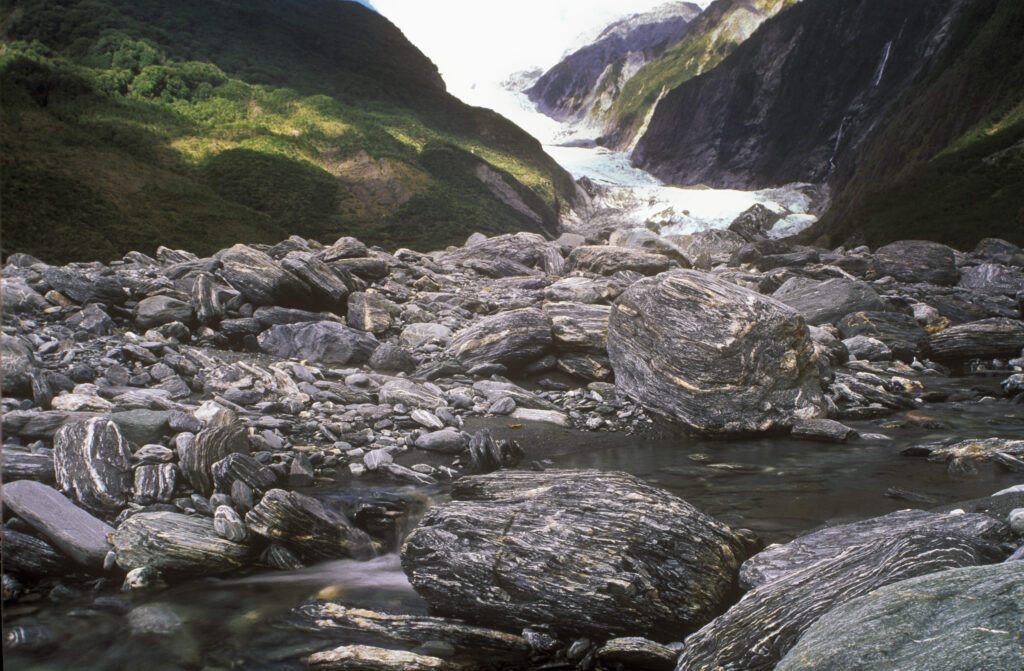 NEW ZEALAND, West Coast, Westland National Park. Huge deposited rocks and the valley carved from the Franz Josef Glacier