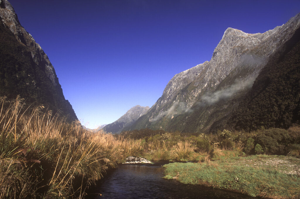 New Zealand, Southland, Fiordland National Park. The Clinton River flowing through the valley below the mountainous peaks