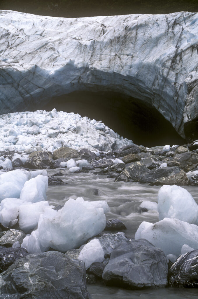 NEW ZEALAND, West Coast, Westland National Park. Huge deposited rocks and the river formed from the Fox Glacier